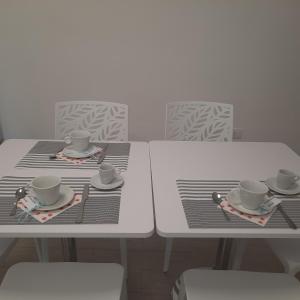 dos mesas blancas con tazas y platillos. en Da Mà en Tortora