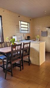 a kitchen with a table and chairs and a counter at Casa de Temporada - Solar Guest House in Saquarema