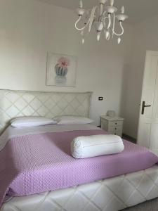 een slaapkamer met een groot bed met paarse lakens en een kroonluchter bij Villa Dei Fiori in Locorotondo