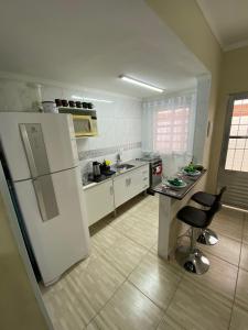 a kitchen with a white refrigerator and two bar stools at Studio - Sol & Mar - 300 metros da praia do Canto do Forte - WI FI e ESTACIONAMENTO gratuito - 50 metros da avenida dos barzinhos in Praia Grande