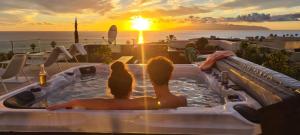 Luxury Villa Rebeka - Heated Pool and Jacuzzi في أديخي: جلوس زوجين في حوض استحمام ساخن مع غروب الشمس