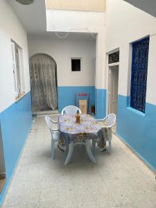 Habitación azul y blanca con mesa y sillas en Le bien être, en Kelibia