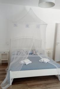 a bedroom with a white bed with a canopy at IL GUFO DELLA MARZA in Ispica