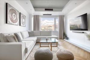 ein Wohnzimmer mit einem weißen Sofa und einem großen Fenster in der Unterkunft Kallirrois 89 Suite in Athen