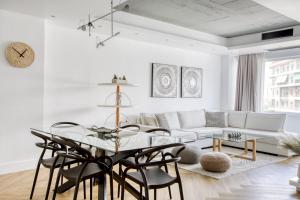 ein weißes Wohnzimmer mit einem Glastisch und Stühlen in der Unterkunft Kallirrois 89 Suite in Athen