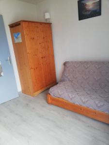 a bedroom with a bed and a wooden cabinet at Courseulla in Courseulles-sur-Mer