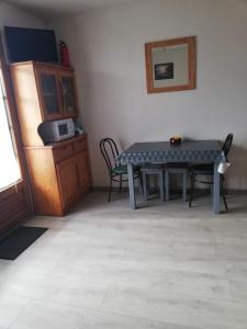 a room with a table with chairs and a microwave at Courseulla in Courseulles-sur-Mer