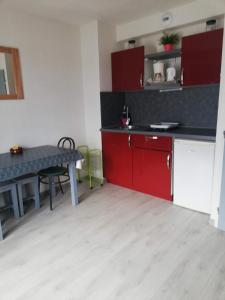 a kitchen with red cabinets and a table at Courseulla in Courseulles-sur-Mer