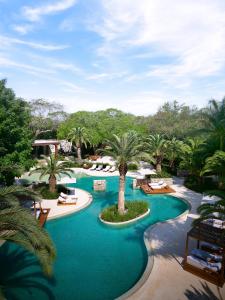 a resort with a pool with palm trees and chairs at Chablé Yucatan in Chocholá