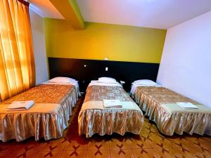 two beds in a room with yellow walls at HOTEL CASA REAL in Tacna