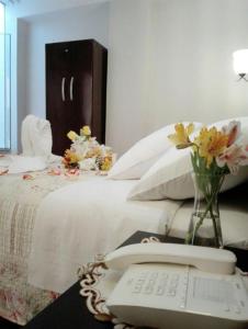 a white bed with a phone and flowers on it at HOTEL CASA REAL in Tacna