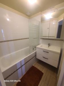 a white bathroom with a sink and a tub and a sink at Les chambrées du bac in Charly-sur-Marne