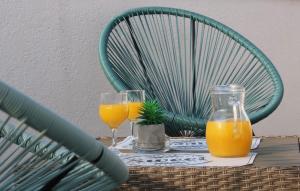 two glasses of orange juice on a table with a chair at Downtown Private Rooms Mandić in Supetar