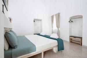 1 dormitorio blanco con 1 cama con manta azul en Casa Vacanze Cisternino alcova nel centro storico, en Cisternino