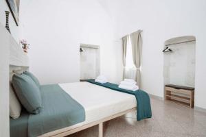 a white bedroom with a bed with a blue blanket at Casa Vacanze Cisternino alcova nel centro storico in Cisternino