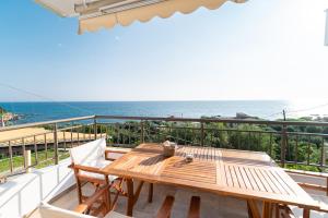 un tavolo in legno con sedie su un balcone con vista sull'oceano di Costa Mare a Paralia Vrachou