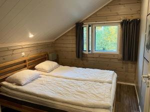 Cama en habitación de madera con ventana en Villa Breikki, Himos en Jämsä