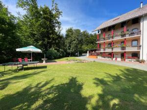 einen Park vor einem Gebäude mit einem Tisch und einem Sonnenschirm in der Unterkunft Apartment & Studio Forest Paradise in Cerkno