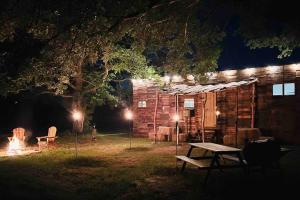 亨茨维尔Cabin 2 - steps from the river!的小木屋在晚上设有野餐桌和壁炉