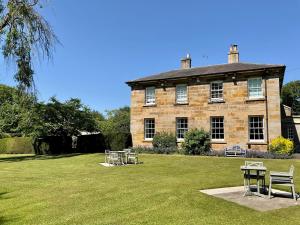 a large brick building with picnic tables in the yard at Chatton Park House Adult Only in Chatton