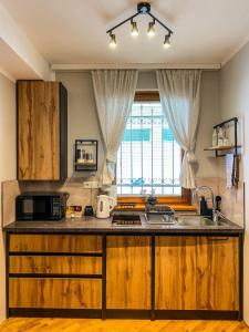 una cucina con armadi in legno, lavandino e forno a microonde di Apartment Mila a Sarajevo