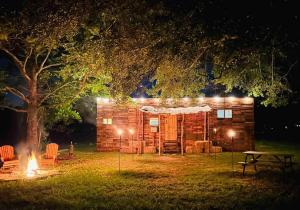 a log cabin with lights in the yard at night at Cabin 2 - steps from the river! in Huntsville