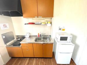 una pequeña cocina con fregadero y microondas en Sapan Hasegawa - Vacation STAY 14781 en Kitakyushu