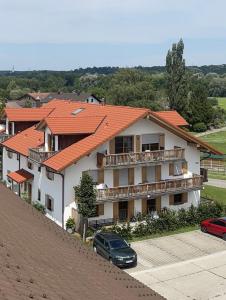 a house with an orange roof with a car parked in front at Ferienwohnungen Thum in Rosenheim