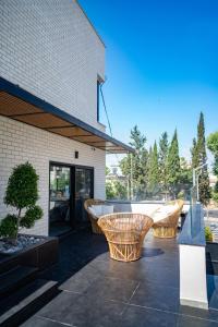 eine Terrasse mit drei Korbstühlen und einem Gebäude in der Unterkunft Rokah Luxury Villa at Ramat HaHayal in Tel Aviv