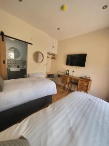 a bedroom with two beds and a desk and a television at The Star Inn - Harbottle - Near Rothbury - Northumberland in Morpeth
