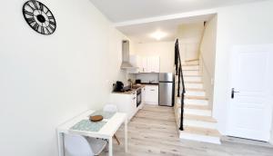 a white kitchen with a table and a clock on the wall at Appartement Cœur de ville in Jonzac