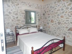 1 dormitorio con cama y pared de piedra en Villa ALONIA en Kalamata