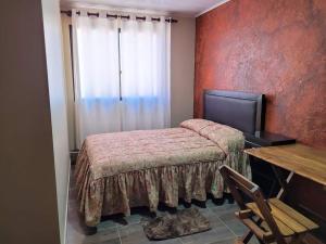 a bedroom with a bed and a table and a window at Torotoro Hostal El Olvido in Torotoro
