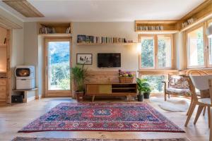 uma sala de estar com um tapete, uma televisão e janelas em LA CASA NEL BOSCO 