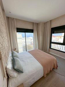 a bedroom with a large bed and two windows at Ático Superior con Terraza Vistas Jacuzzi y Wifi - Poniente Penthouse in Tarifa