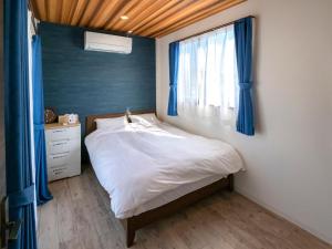 een slaapkamer met een bed met blauwe gordijnen en een raam bij Another sky - Vacation STAY 90163v in Miyazaki
