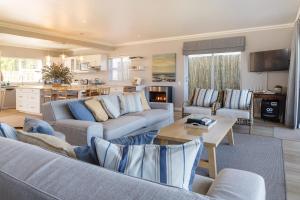 a living room with two couches and a kitchen at Seapearl Oceanfront Villa and Cottage in Hermanus