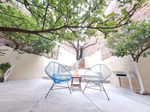 two chairs and a table in a courtyard with trees at Beautiful rustic-style house close to downtown in Guanajuato