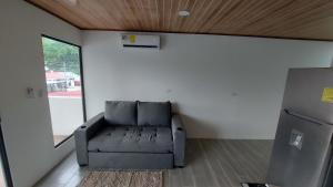 ein Wohnzimmer mit einem Sofa und einem Kühlschrank in der Unterkunft Casas Dñ Juanita in Jacó