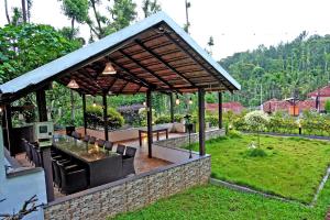 um pavilhão com uma mesa e cadeiras num jardim em Jungle Greens Homestay - Safari Ride & Near to View Points em Chikmagalūr