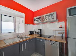 a kitchen with a sink and a red wall at L'Oiseau Bleu - Superbe vue mer in Les Trois-Îlets