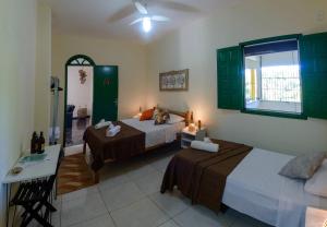 a hotel room with two beds and a window at Casarão das artes hospedaria in Cumuruxatiba