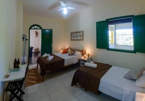 Una habitación de hotel con dos camas y una ventana. en Casarão das artes hospedaria, en Cumuruxatiba
