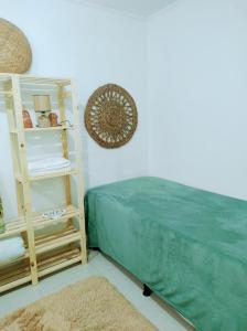 a bedroom with a green bed and a shelf at Morada Héstia in Imbé