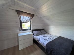 a small bedroom with a bed and a window at Malaga in Gąski