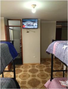 a room with two beds and a tv on the wall at Hotel San Francisco in Cajamarca