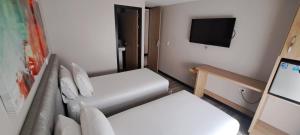 a small room with two beds and a flat screen tv at Hotel Olaya Plaza in Pereira