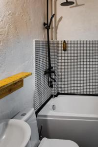 a bathroom with a white toilet and a bath tub at Hydeout Bakuriani in Bakuriani