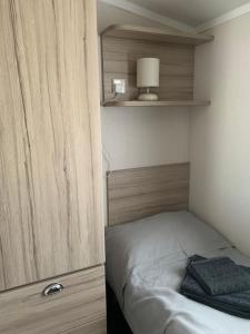 a small bedroom with a bed and a wooden wall at Hot tub breakaways with castle view in Lincolnshire