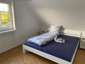 um quarto com uma cama com lençóis azuis e uma janela em Zaunkönigin em Norden